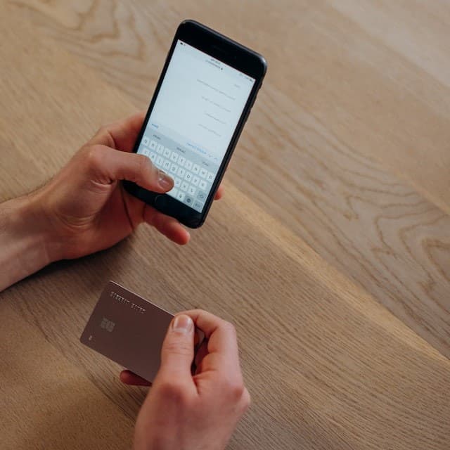 Persona con tarjeta de crédito y celular en sus manos